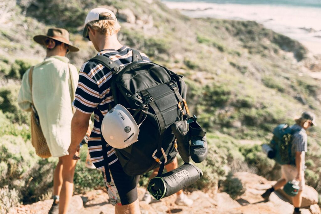 Group of hikers with backpacks exploring sunlit hills, enjoying a summer outdoor adventure.