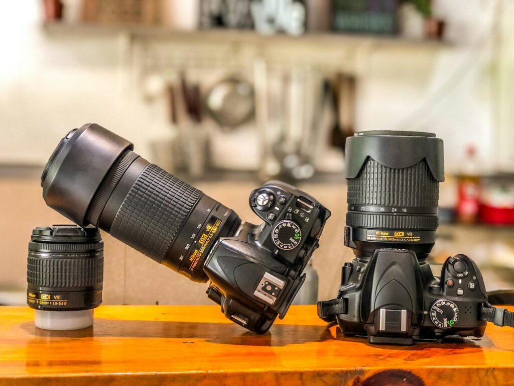 Close-up of DSLR cameras and lenses on a wooden table indoors, ideal for photography enthusiasts.