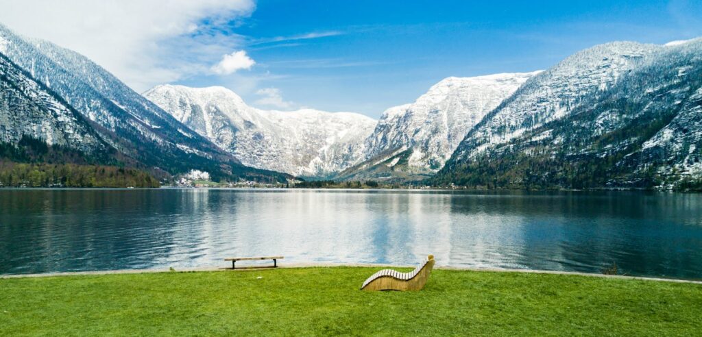 Beautiful view of Hallstatt lake surrounded by snowy mountains with benches in the foreground.
