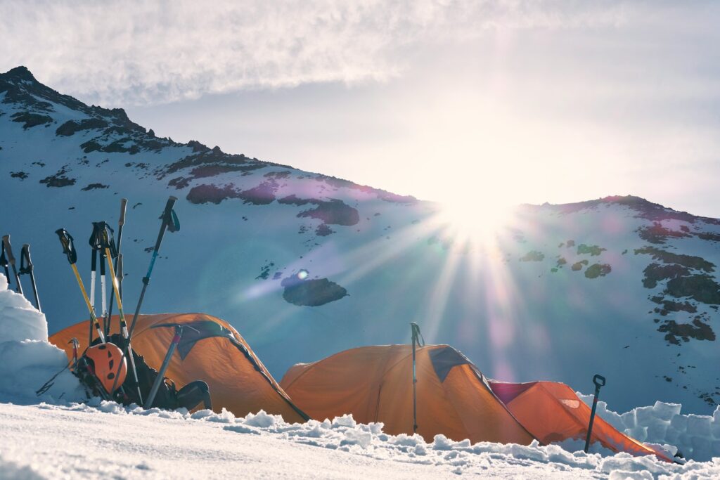 three yellow and red dome tents on snow capped mountain