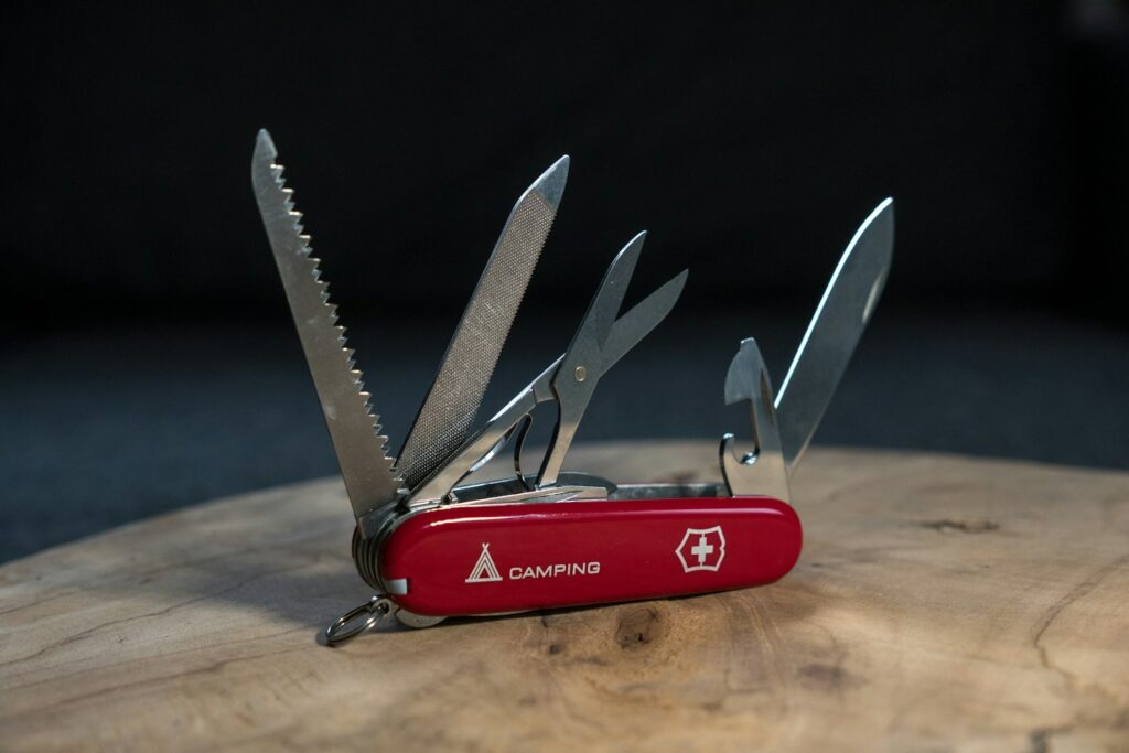 A red swiss army knife sitting on top of a wooden table