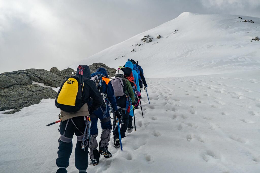 Adventurers climbing a snow-covered mountain in winter with climbing gear.