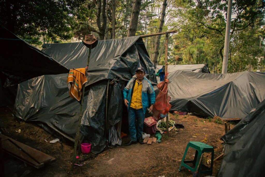 A man stands in a makeshift tent in a forest in Bogota, Colombia.