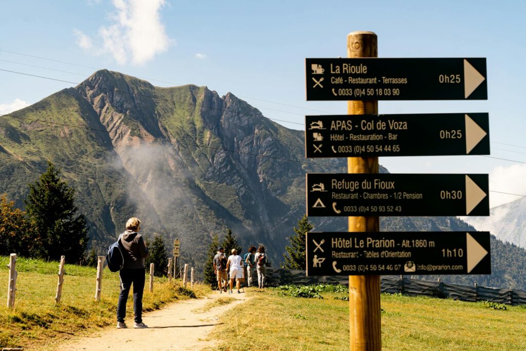 Hikers on a mountain trail with a signpost view at a scenic location.