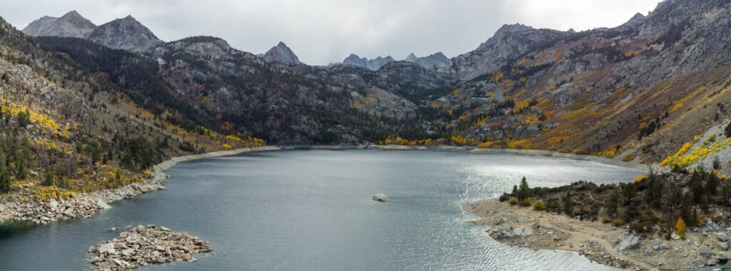 Aerial view of Lake Sabrina surrounded by mountains and autumn colors in Bishop, California.