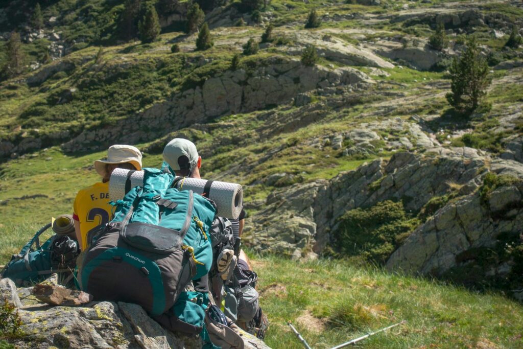 Two backpackers taking a break on a mountain hike, enjoying the view.