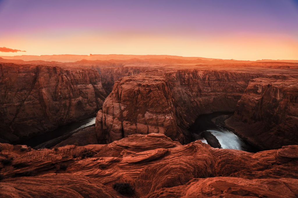 Captivating sunset view of Horseshoe Bend canyon with the Colorado River, showcasing dramatic rock formations and vibrant skies.