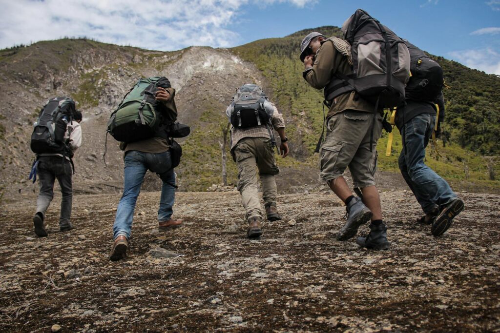 Five hikers with backpacks trekking up a mountain path in West Sumatra, Indonesia.