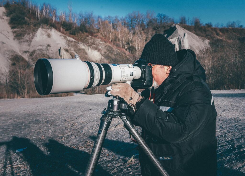 Man using telephoto lens camera outdoors capturing scenic views.