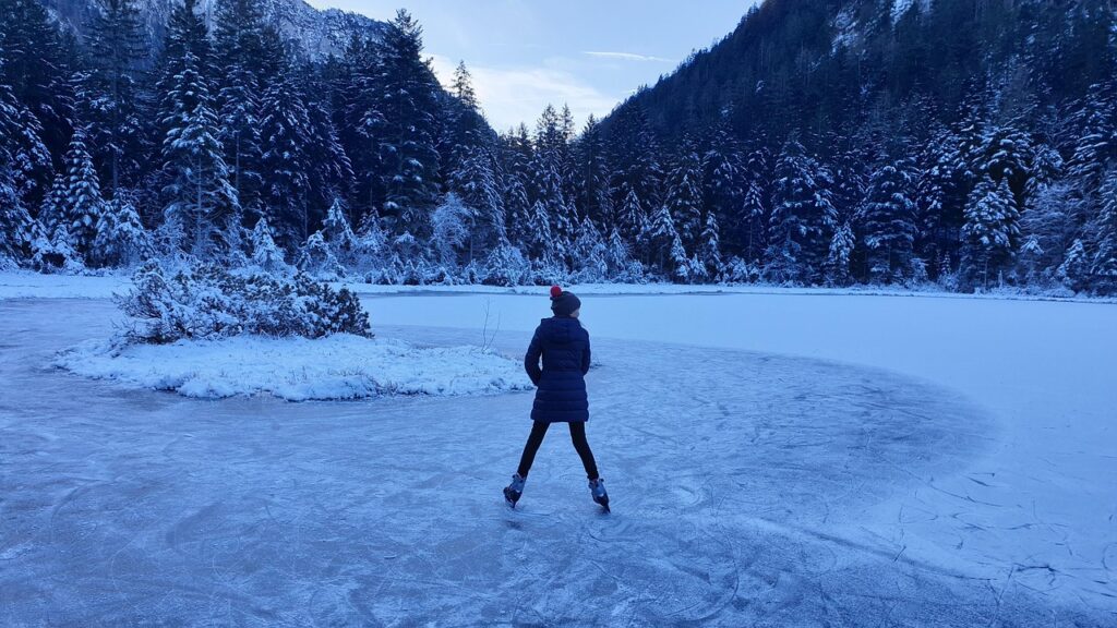 A person stands on an ice rink surrounded by snow, showcasing a winter scene of outdoor skating.