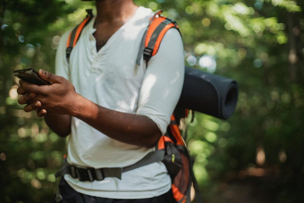 A man in the forest checking his smartphone during a summer hike.