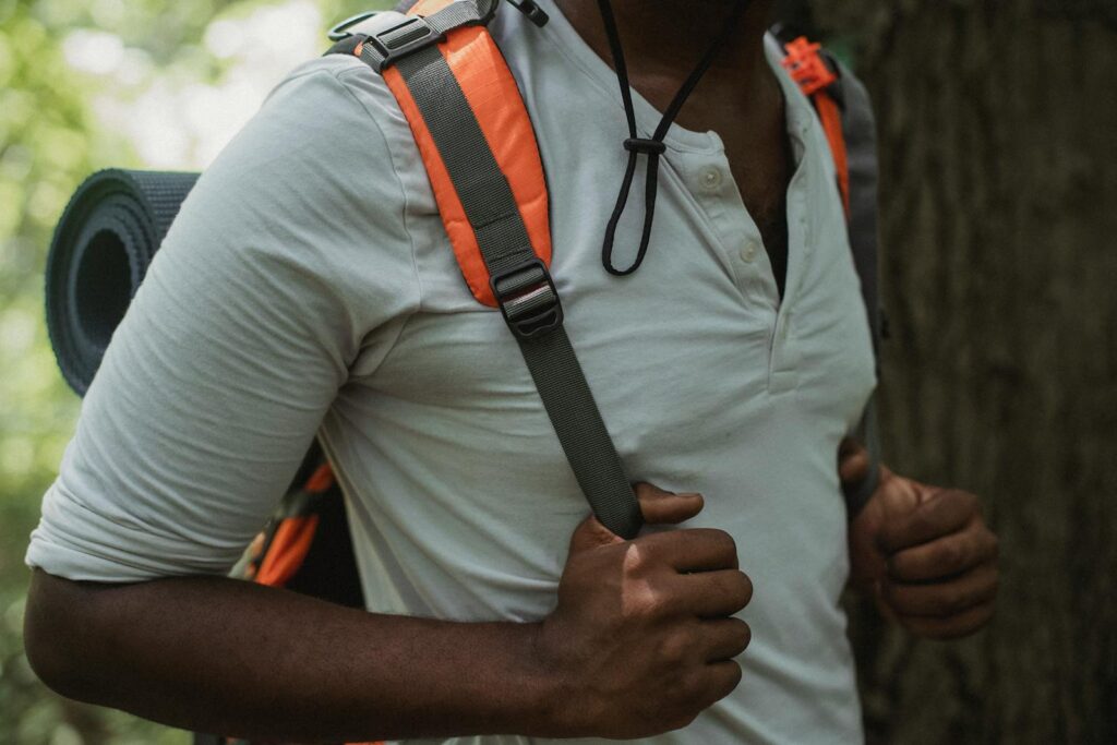 A man hiking in a forest carrying a backpack, enjoying a summertime adventure.
