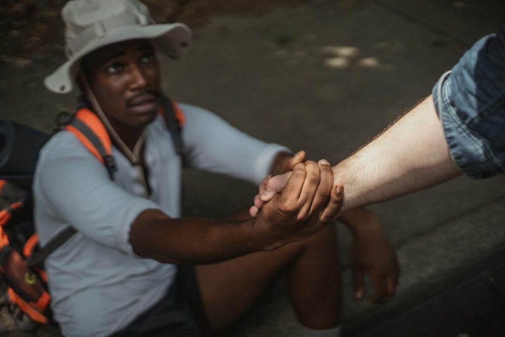 A hiker being helped up, symbolizing support and friendship in an outdoor setting.