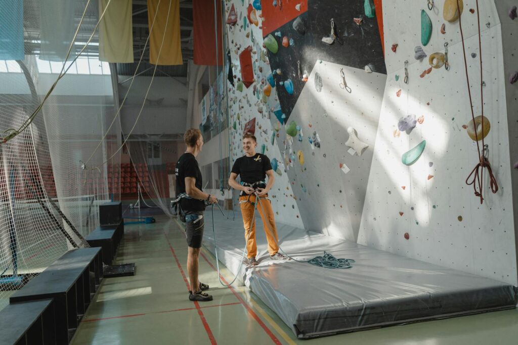 Two men preparing for indoor rock climbing at a climbing gym.