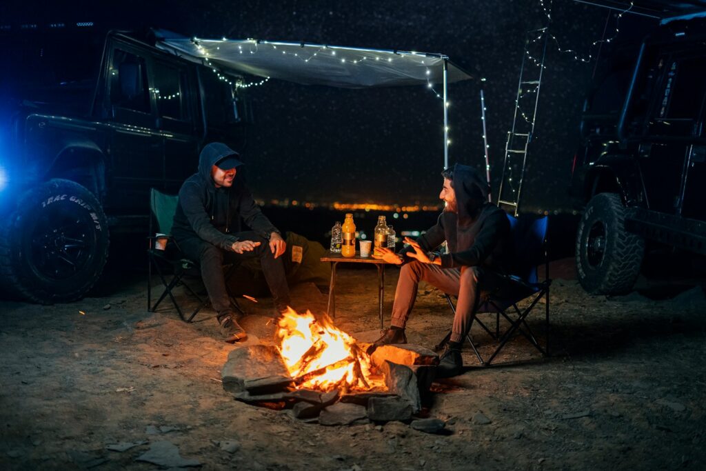 two people sitting around a campfire at night