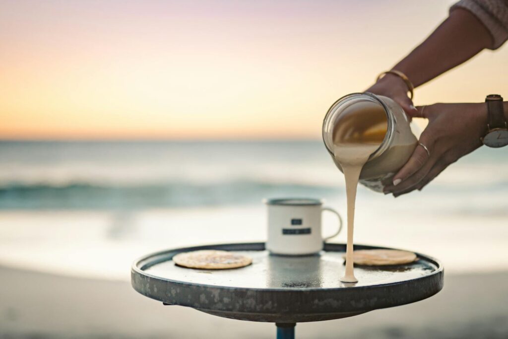 Pouring pancake batter by the ocean at sunrise, embracing morning tranquility.