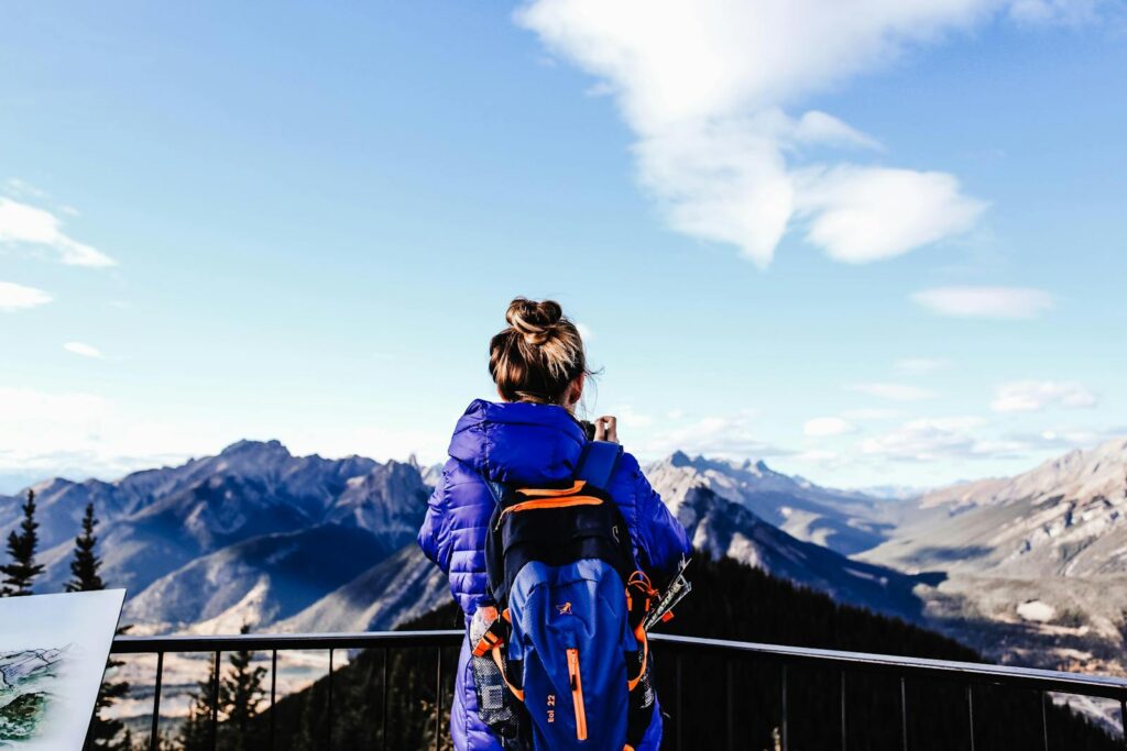 A woman hiker views stunning mountains from a deck on a clear day.