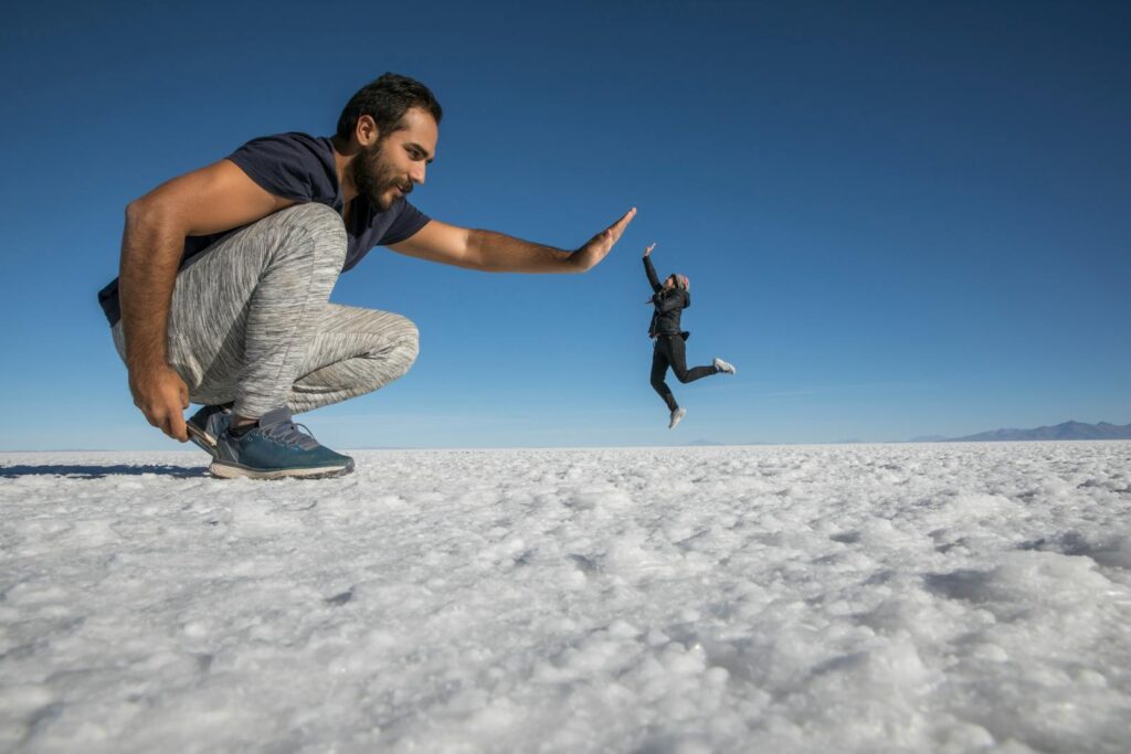 Creative perspective photography of a high five at Salar de Uyuni, Bolivia, showcasing fun interactions.