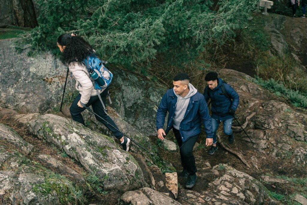 A group of young adult hikers climbing a rocky forest trail, enjoying outdoor adventure and exploration.