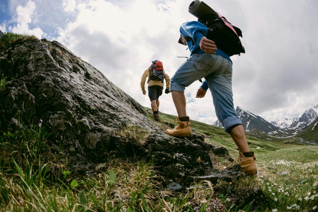 Two hikers climb a rocky trail in picturesque mountain scenery, signaling an adventurous expedition.