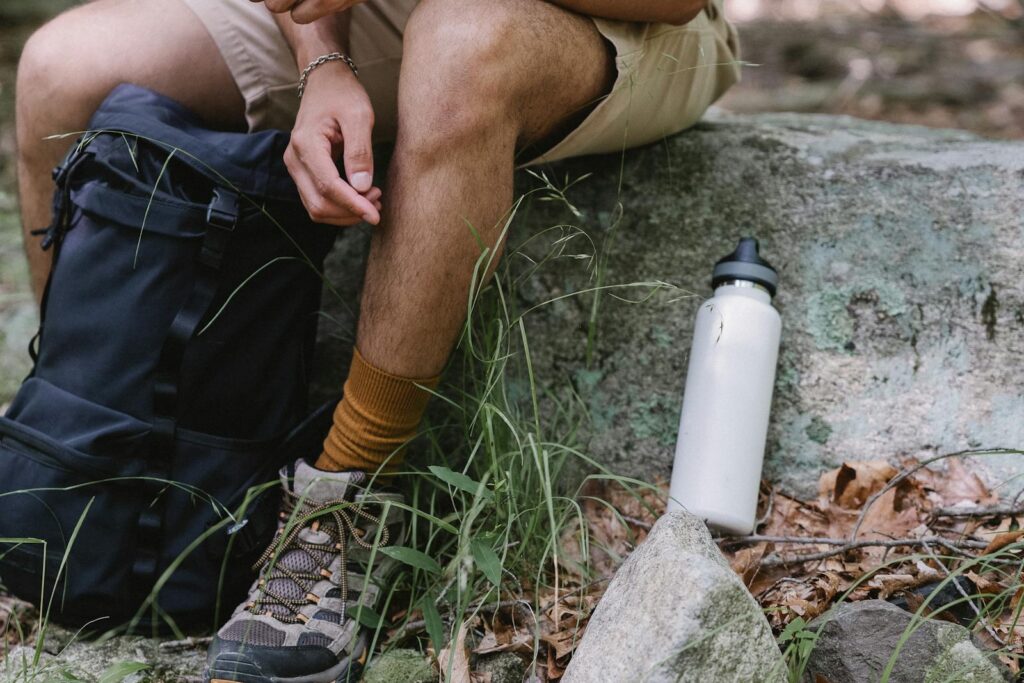 Close-up of a hiker with gear, resting on a stone outdoors.