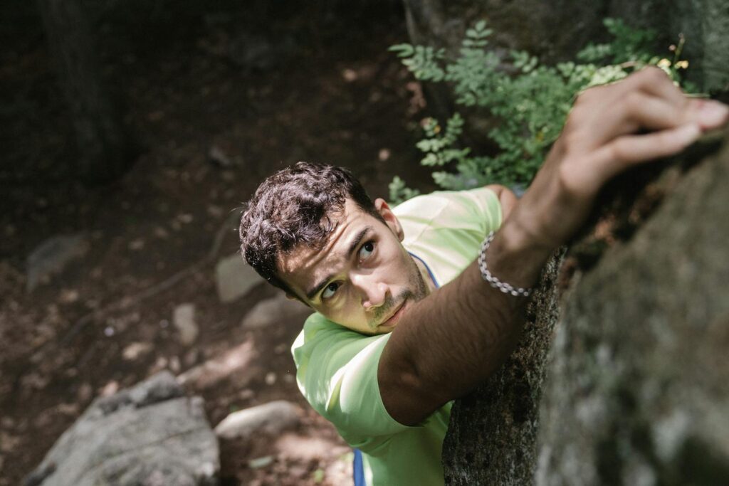 Focused man climbing a rock outdoors, capturing adventure and determination.