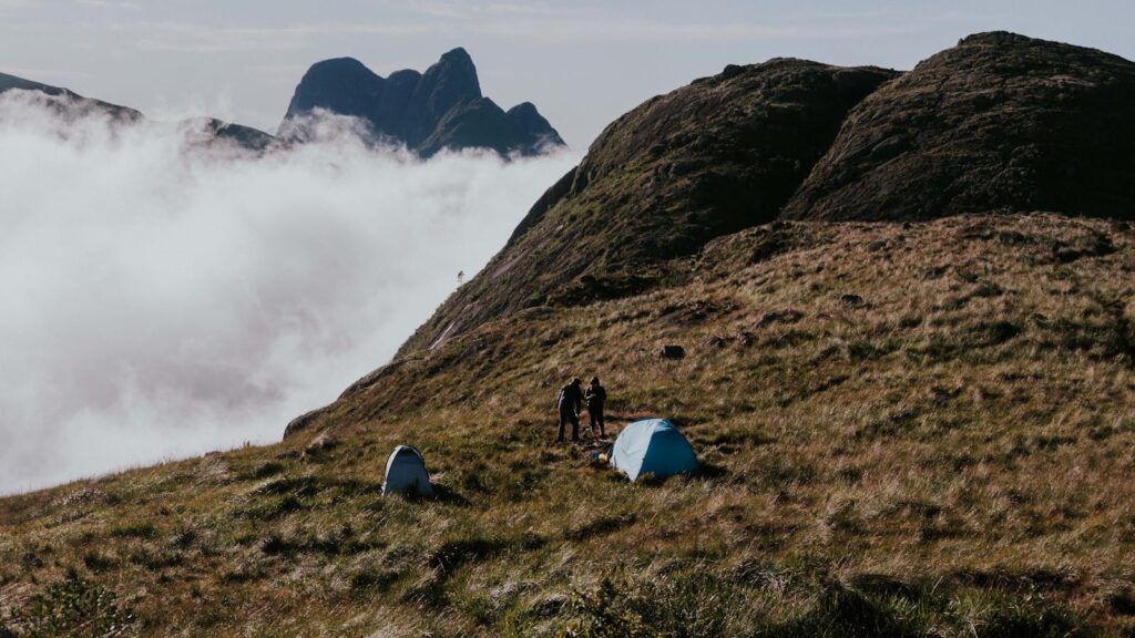 Two tents pitched on a misty mountain with distant peaks, an ideal setting for adventure seekers.