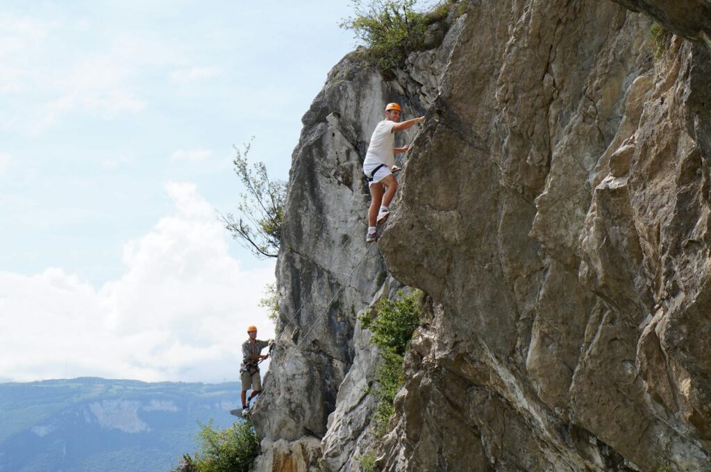 Two climbers ascend a rugged cliff, showcasing adventure and skill.
