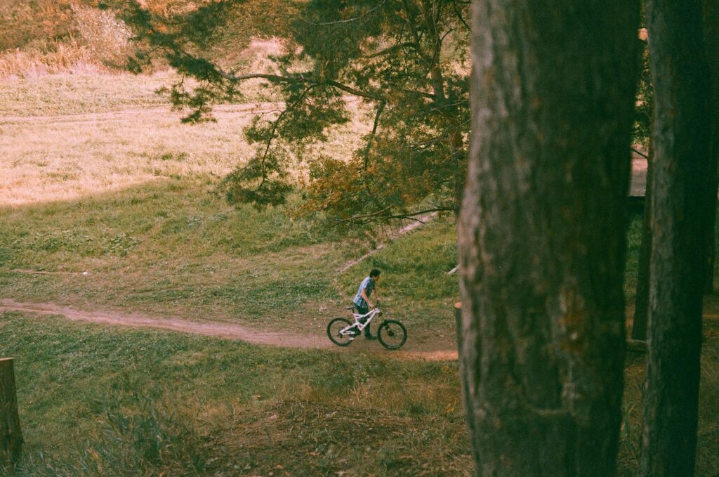 An adult cyclist rides through a tranquil forest path during the fall season.
