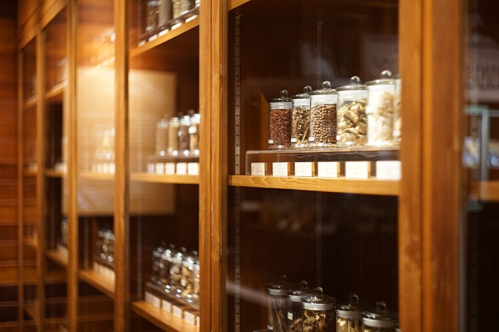 A wooden shelf displaying various jars of herbs and spices, labeled neatly, with warm ambient lighting highlighting the collection.