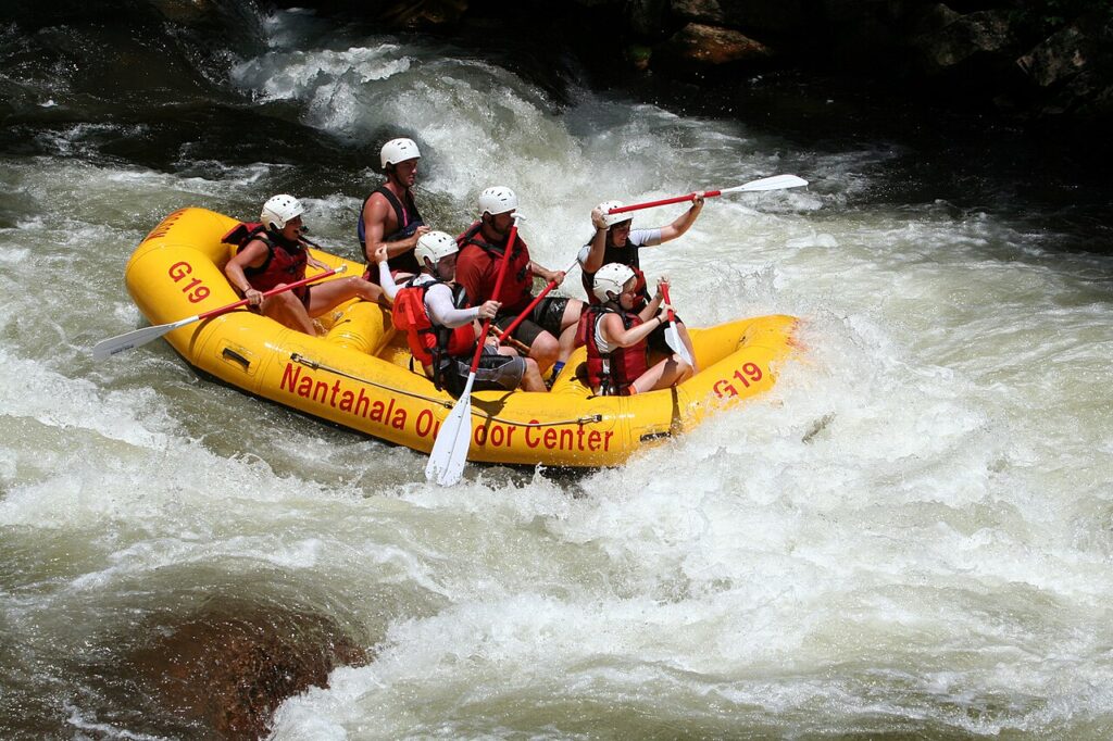 A group of six people in helmets paddle a bright yellow raft through turbulent whitewater, showcasing an exciting outdoor adventure.