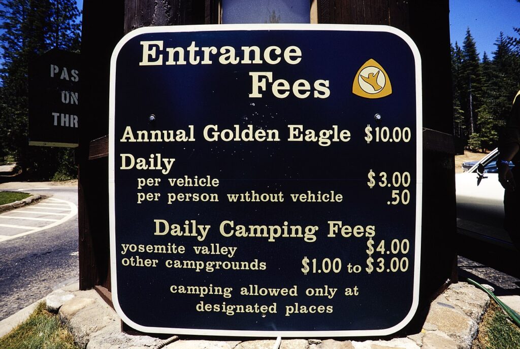 Sign displaying entrance fees for a park: Annual Golden Eagle $10, daily fees $3 per vehicle, $0.50 per person; camping fees vary.