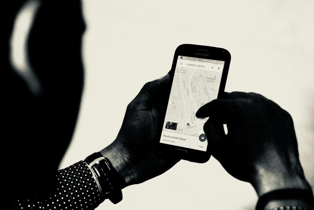A person's hand holding a smartphone with a map displayed, showing Musiliu Smith Street, Lagos, in black and white.