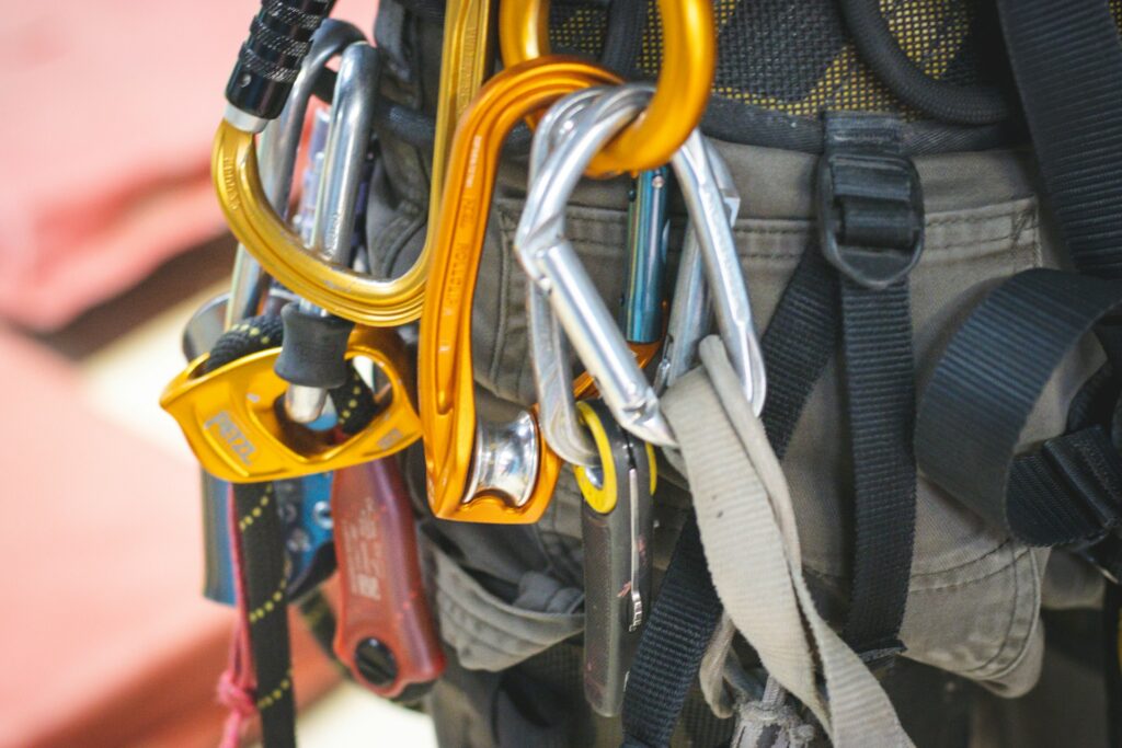 Close-up of a climbing harness with various colorful carabiners and gear attached, highlighting adventure tools in a climbing environment.