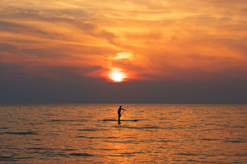 silhouette of person on boat holding paddle during golden hour