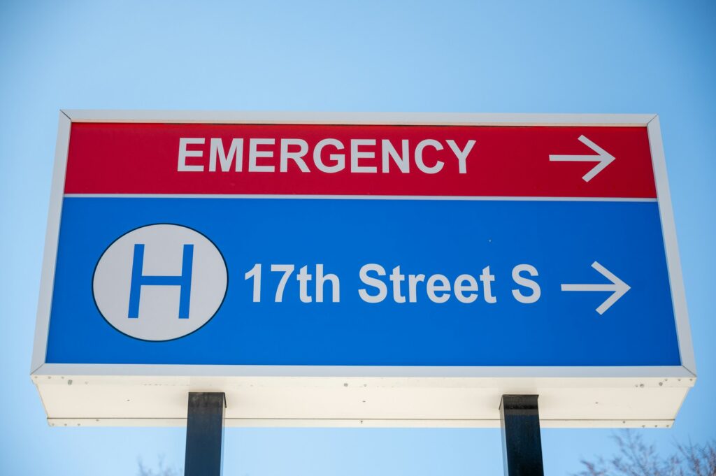 A directional sign indicating "Emergency" and "17th Street S," with arrows pointing right for both locations against a clear blue sky.