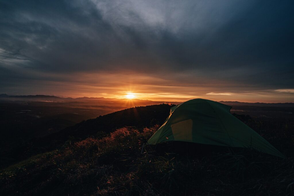 a tent pitched up on a hill at sunset