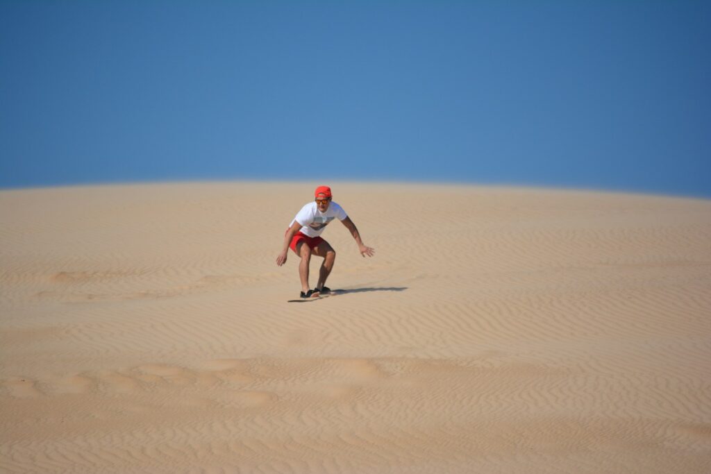 a man riding a skateboard down a sandy hill