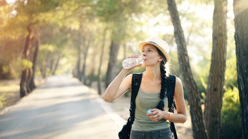 a woman in a hat drinking water from a bottle
