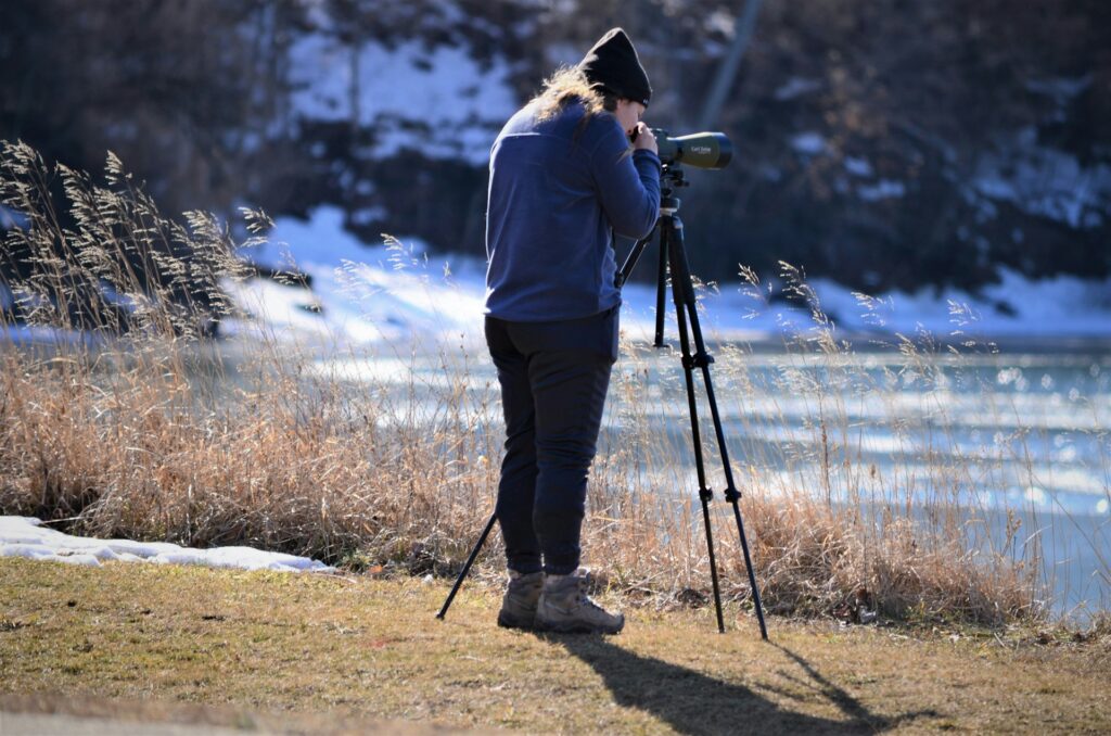 Person in blue jacket and black pants standing on brown field during daytime photo.