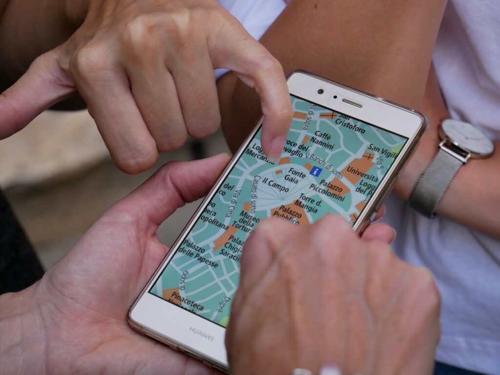 Two hands interacting with a smartphone map, highlighting locations and directions while exploring a city.