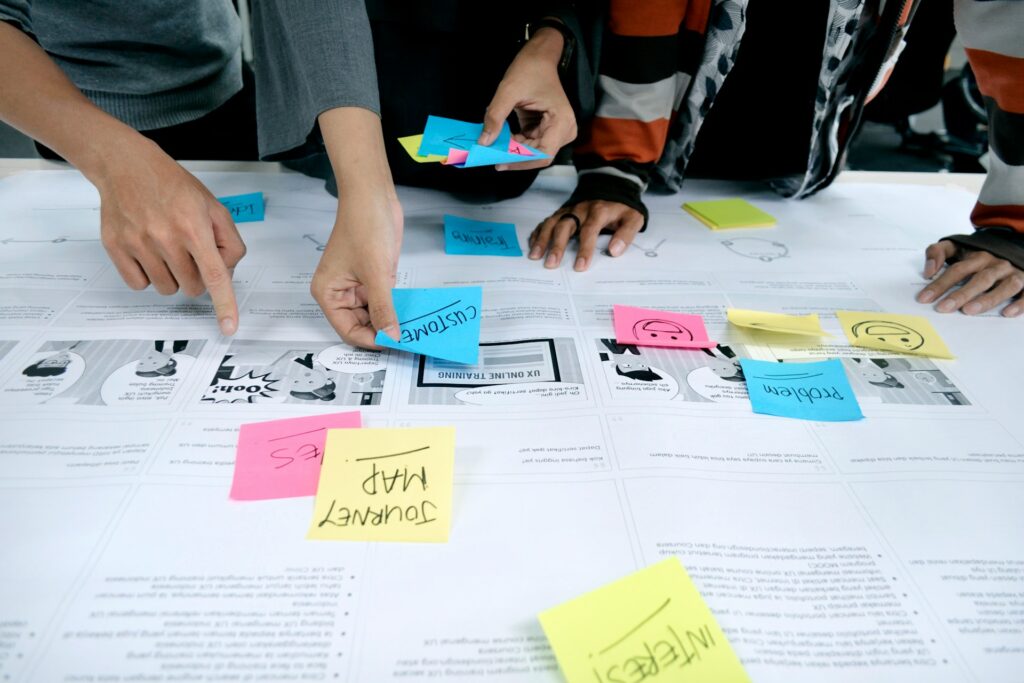 Hands interacting with sticky notes on a storyboard, illustrating user journey and feedback during a collaborative brainstorming session.