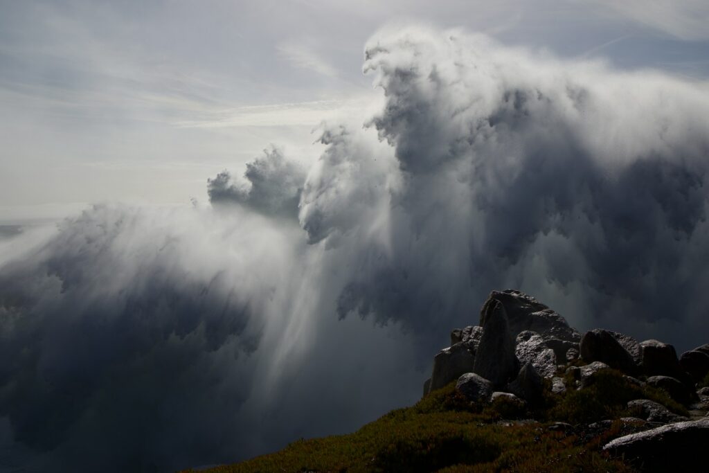 A very large cloud moving over a mountain