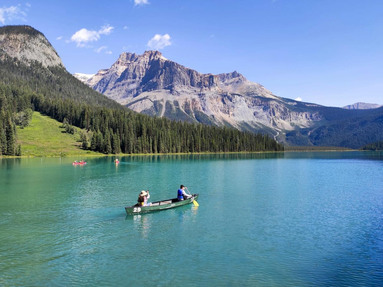 Two people canoeing on the pristine waters of Emerald Lake with majestic mountain views.