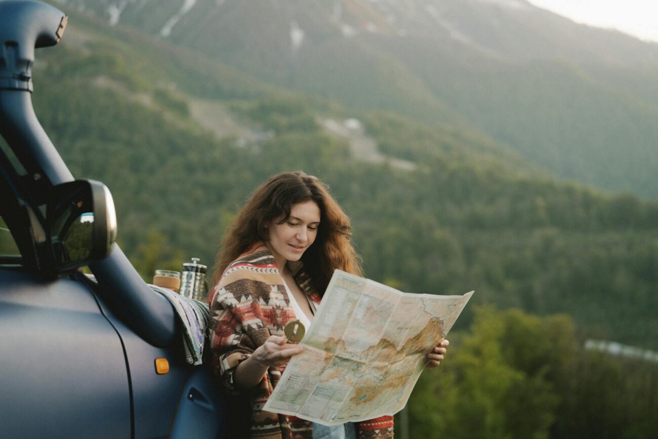 A woman enjoys a scenic mountain road trip, using a map to navigate picturesque landscapes.