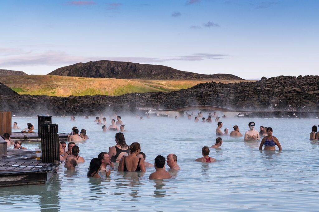 People relax and enjoy the warm waters of the Blue Lagoon hot springs, surrounded by stunning natural scenery.