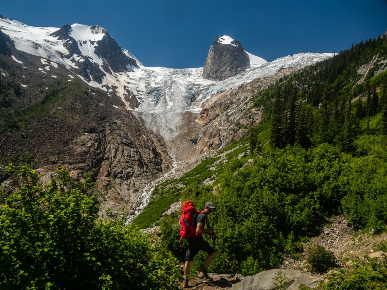 person climbing on mountain near trees during daytime