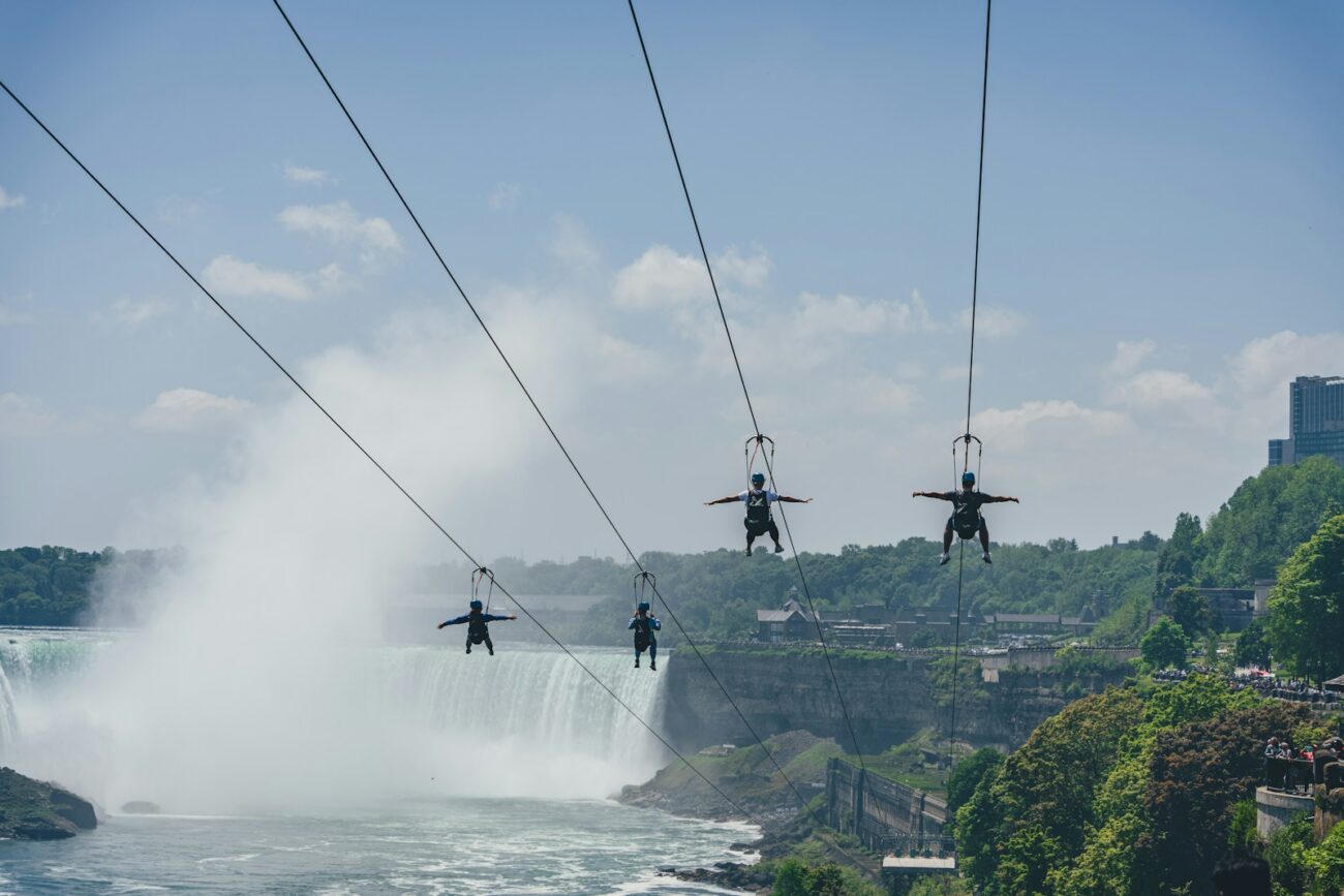 a group of people on a rope above a waterfall
