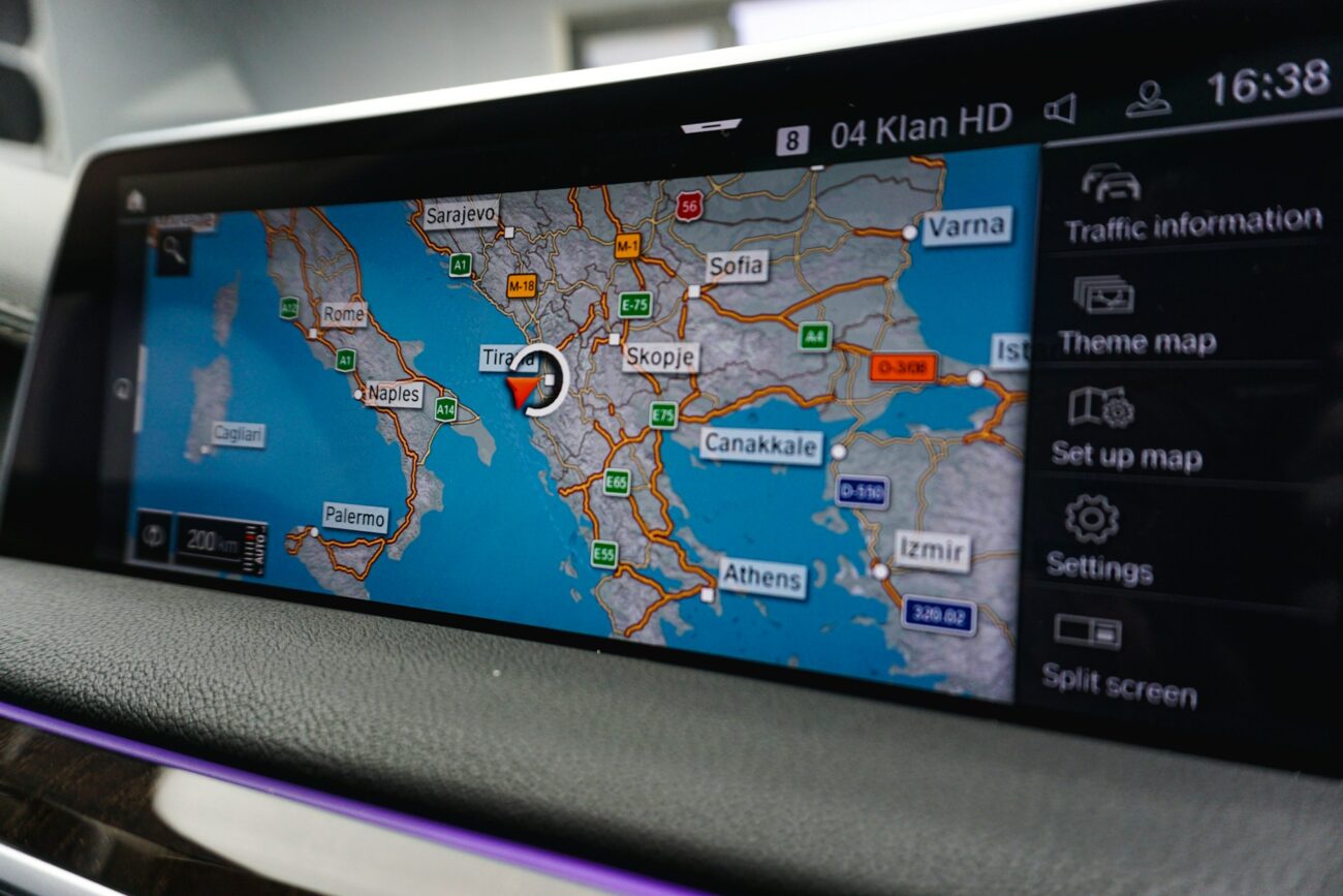 A car navigation screen displaying a map of the Balkans, highlighting Tirana, with route options and settings on the right.